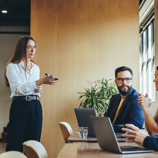 Confident young businesswoman discussing her marketing strategy and ideas with her team. Female manager giving a presentation during a meeting with her colleagues in a modern workspace.